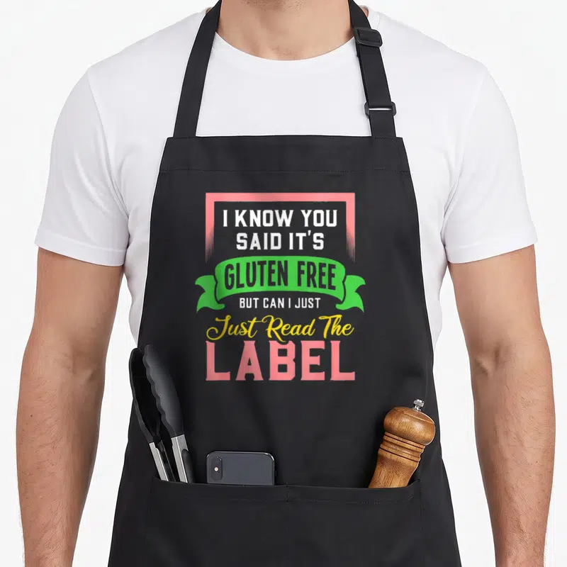 Gluten free celiac awareness apron - Stacked pink green and yellow text reading I know you said gluten free read — shown on a black cotton canvas apron against a white background