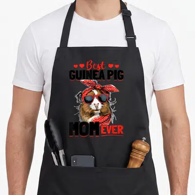 Pet rodent animal apron - Cartoon guinea pig with red sunglasses and bandana surrounded by hearts and text — shown on a black cotton canvas apron against a white background