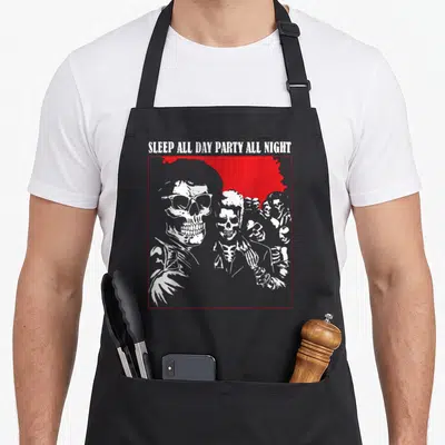 Sleep horror apron - White skeleton line art in red square frame with SLEEP ALL DAY PARTY ALL NIGHT text — shown on a black cotton canvas apron against a white background