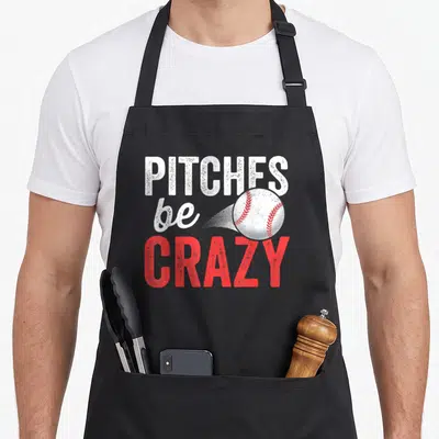 Pun baseball apron - Stacked Pitches be Crazy text with a baseball and motion lines in white and red — shown on a black cotton canvas apron against a white background