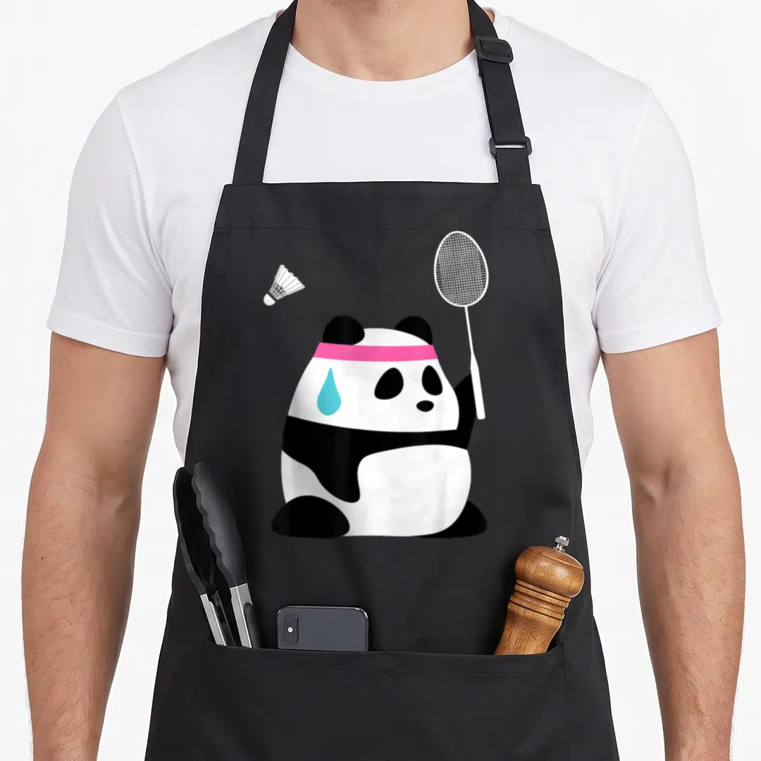 Exhausted animal apron - Cartoon panda with pink headband holding badminton racket, blue sweat drop, shuttlecock nearby — shown on a black cotton canvas apron against a white background