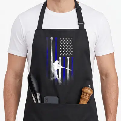 Player american flag apron - White baseball player silhouette over blue and white vertical bat stripes and star field — shown on a black cotton canvas apron against a white background
