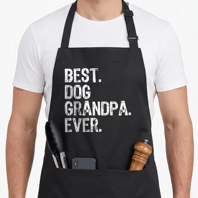Dog grandpa apron - White stacked text reading best dog grandpa ever on grey background — shown on a black cotton canvas apron against a white background