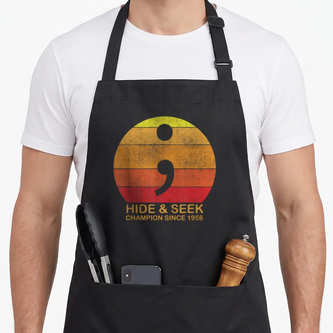 Coding crew apron - Grey semicolon over yellow orange red stripes with Hide & Seek text — shown on a black cotton canvas apron against a white background