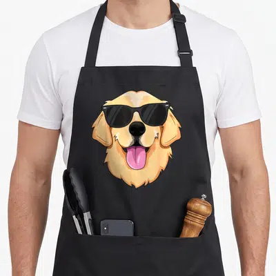 Sunglass golden retriever apron - Cartoon golden dog head wearing black sunglasses with pink tongue sticking out — shown on a black cotton canvas apron against a white background