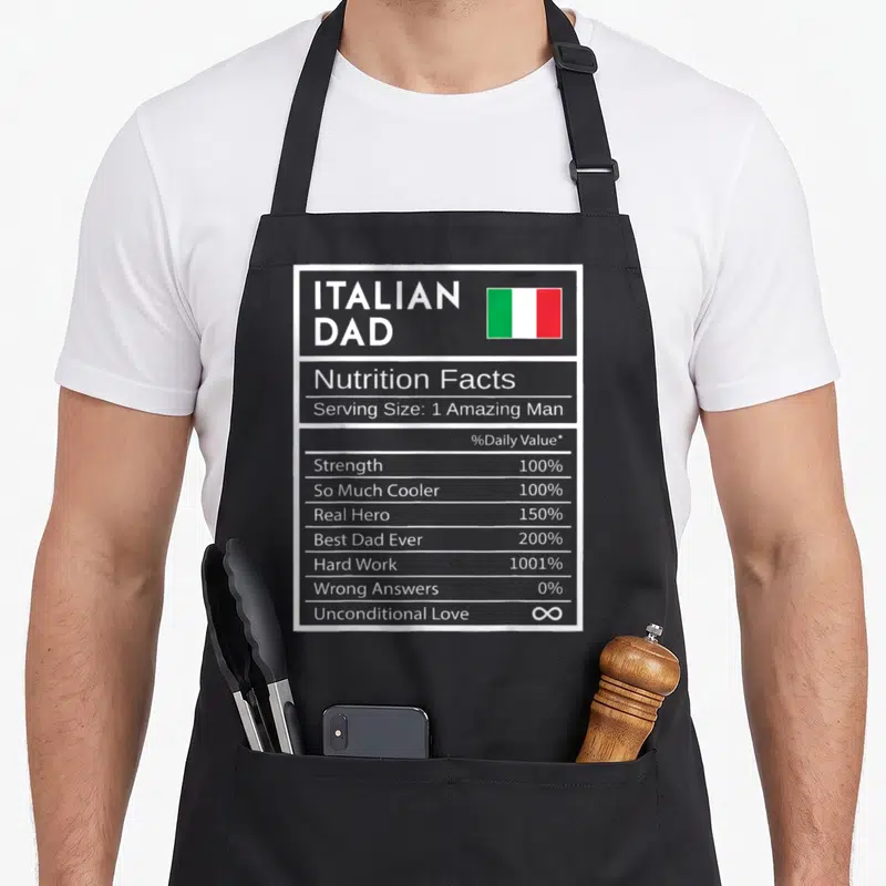 Fact italian aprons - Italian Dad nutrition label with flag, 1001% hard work, infinite love text — shown on a black cotton canvas apron against a white background