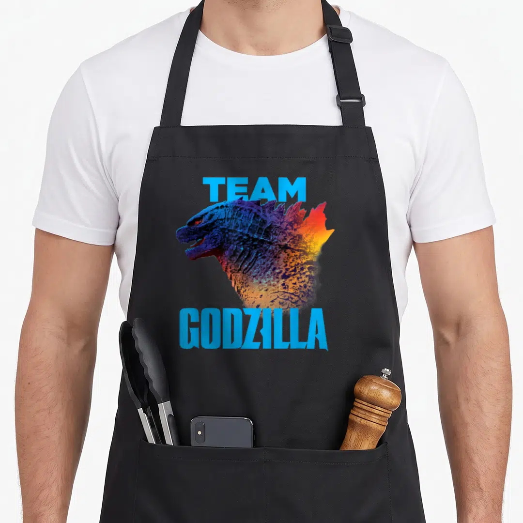 Kong fanboy apron - Realistic Godzilla head with light blue TEAM GODZILLA text and blue orange yellow gradient coloring — shown on a black cotton canvas apron against a white background