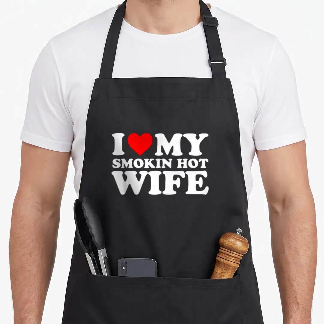 Smokin wife apron - I MY SMOKIN HOT WIFE with red heart between I and MY in white stacked typography — shown on a black cotton canvas apron against a white background