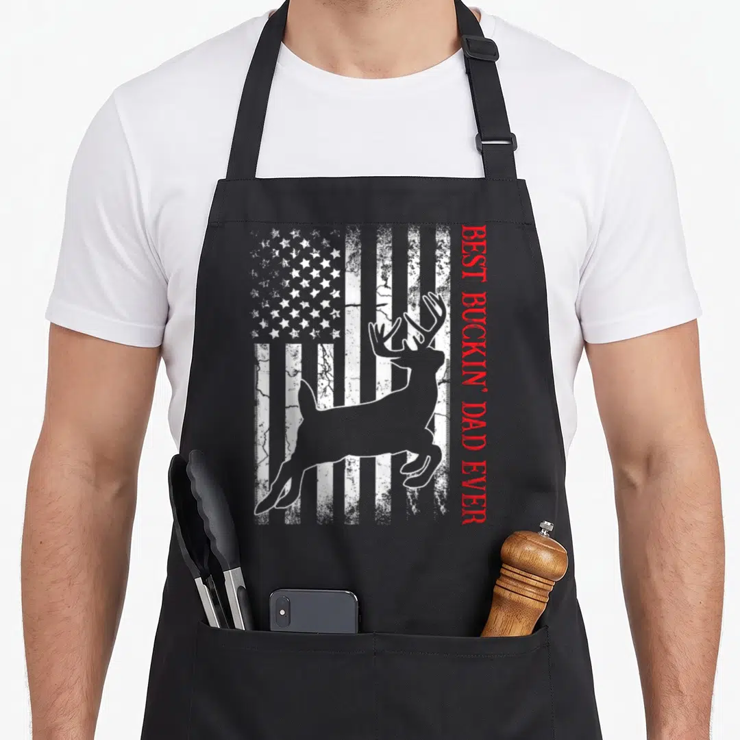 Buckin american flag apron - Grey deer silhouette over distressed flag with vertical red text — shown on a black cotton canvas apron against a white background