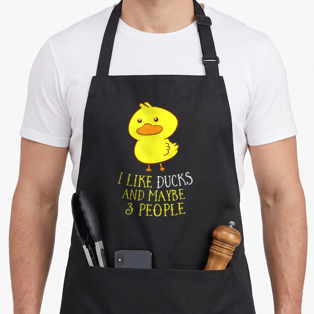 Maybe duck apron - Cartoon yellow duck above stacked text I LIKE DUCKS AND MAYBE 3 PEOPLE — shown on a black cotton canvas apron against a white background