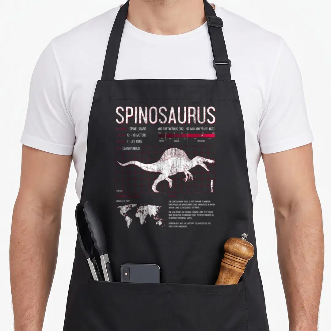 Spinosaurus science apron - Distressed white and red Spinosaurus data grid with human scale silhouette and world map — shown on a black cotton canvas apron against a white background
