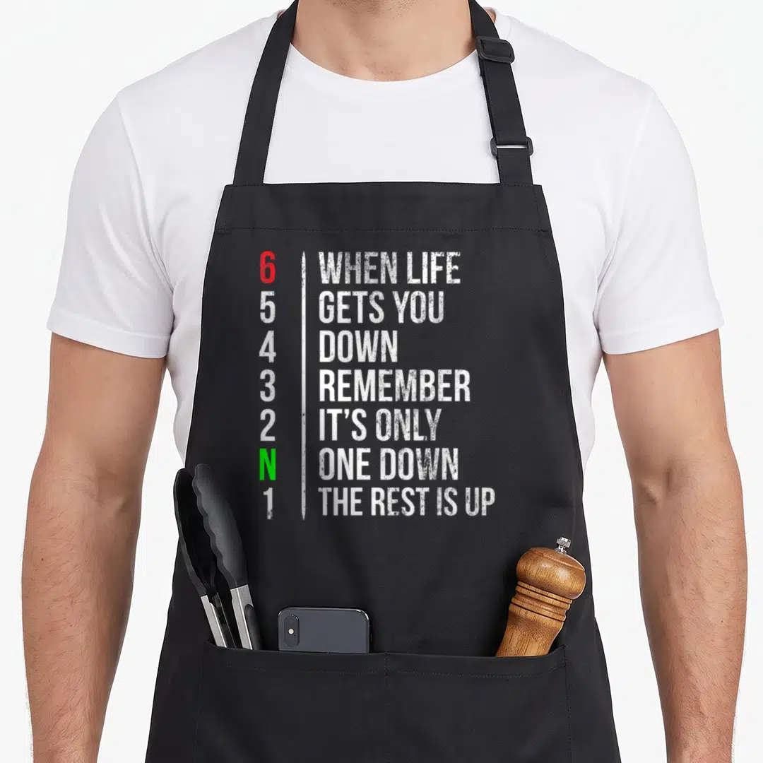 Motorbike motorcycle apron - Gear shift numbers 6 through 1 with motivational quote in white red and green text — shown on a black cotton canvas apron against a white background