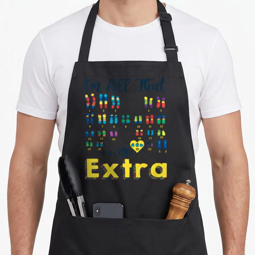 Chromosome syndrome an extra apron - Colorful chromosome pairs numbered 1 to 22 with a yellow heart around pair 21 — shown on a black cotton canvas apron against a white background