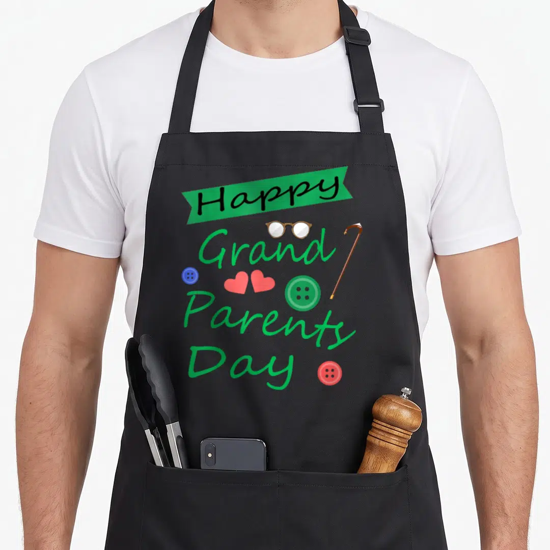 Grandparent generations apron - Happy Grand Parents Day text with glasses cane buttons and hearts in green red blue — shown on a black cotton canvas apron against a white background