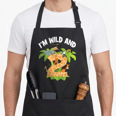 Wild 2nd apron - I'M WILD AND text over giraffe-print number 2 with monkey zebra elephant toucan palm leaves — shown on a black cotton canvas apron against a white background