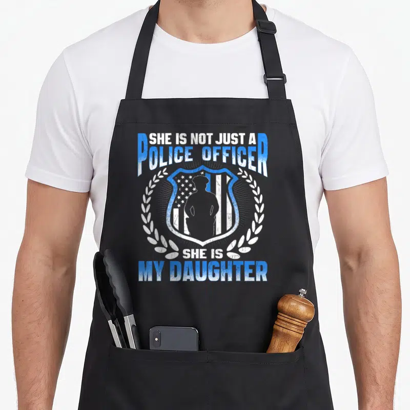 Brave mom daughter apron - Distressed blue and white badge with police officer silhouette and laurel wreath text — shown on a black cotton canvas apron against a white background