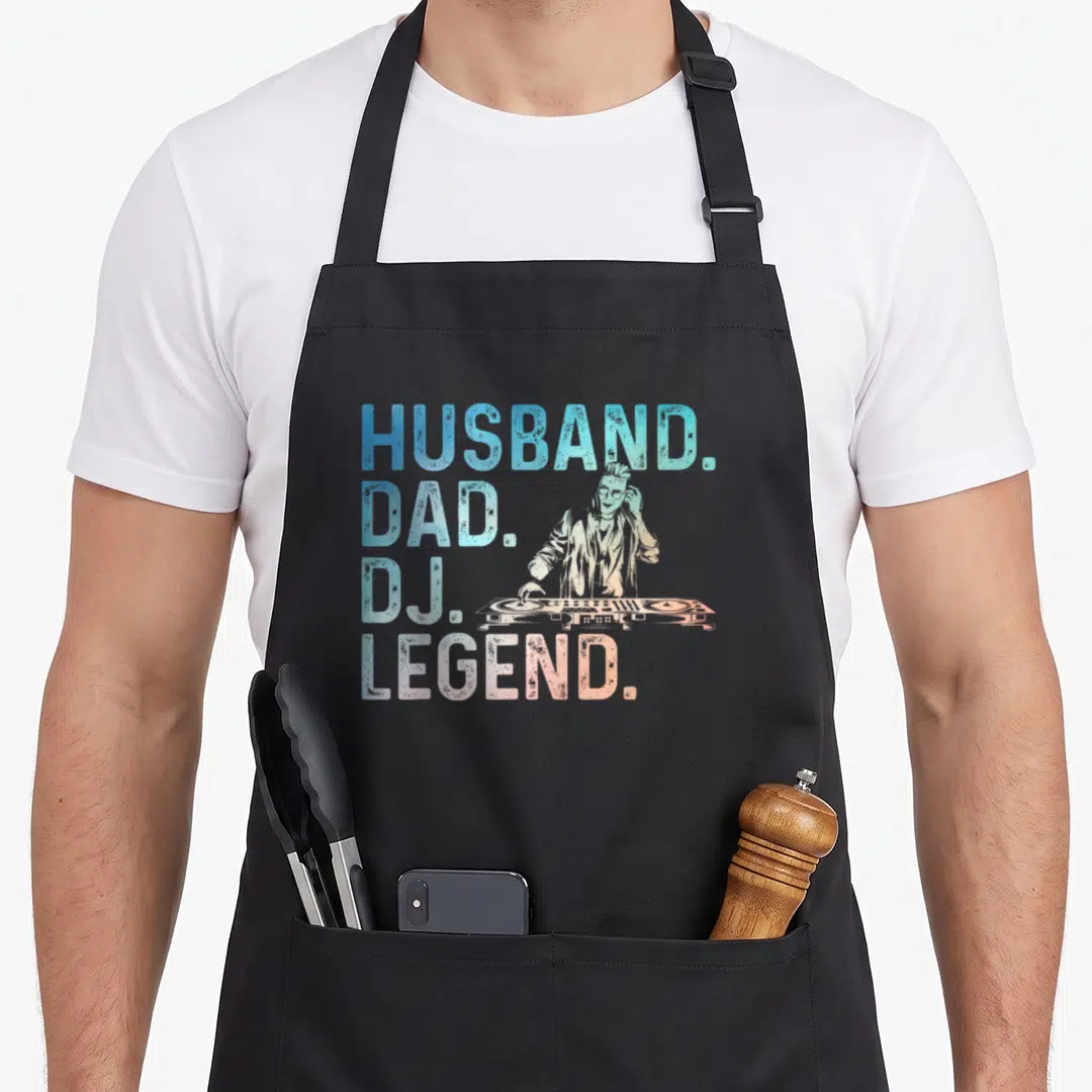 Disc husband apron - Stacked HUSBAND DAD DJ LEGEND text with retro DJ mixing on controller in blue cyan and orange — shown on a black cotton canvas apron against a white background