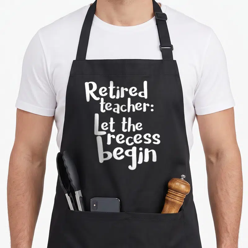 Funny retired teachers apron - White stacked text reading Retired teacher Let the recess begin — shown on a black cotton canvas apron against a white background