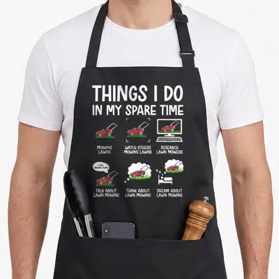 Mower gardener apron - Cartoon red lawn mower scenes with text about mowing obsession — shown on a black cotton canvas apron against a white background