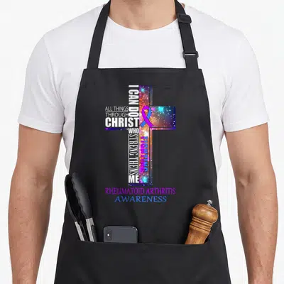 Rheumatoid christmas apron - Cross typography with I can do all things text and purple blue awareness ribbon — shown on a black cotton canvas apron against a white background