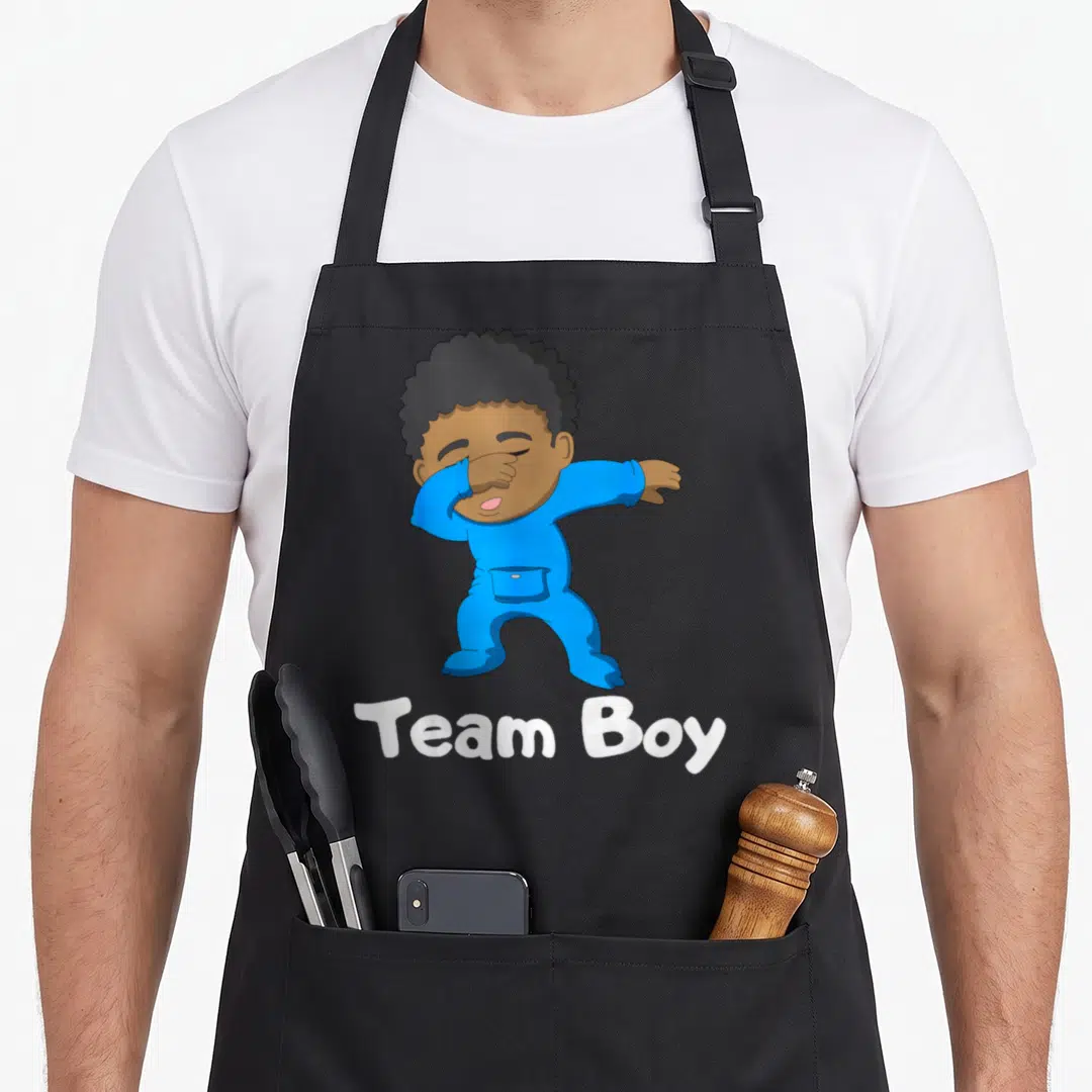 Gender dabbing boys apron - Cartoon baby in blue onesie dabbing with white Team Boy text underneath — shown on a black cotton canvas apron against a white background