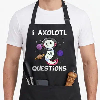 Onesie question apron - Axolotl in space helmet surrounded by planets with i AXOLOTL QUESTIONS text — shown on a black cotton canvas apron against a white background