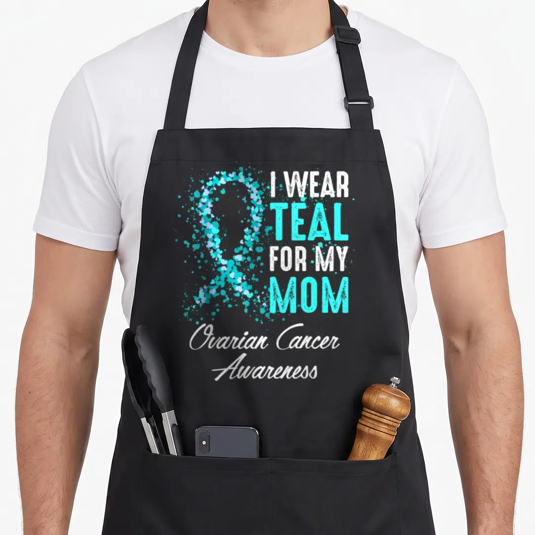Ovarian mother's apron - Teal heart ribbon and stacked text I wear teal for my mom ovarian cancer awareness — shown on a black cotton canvas apron against a white background