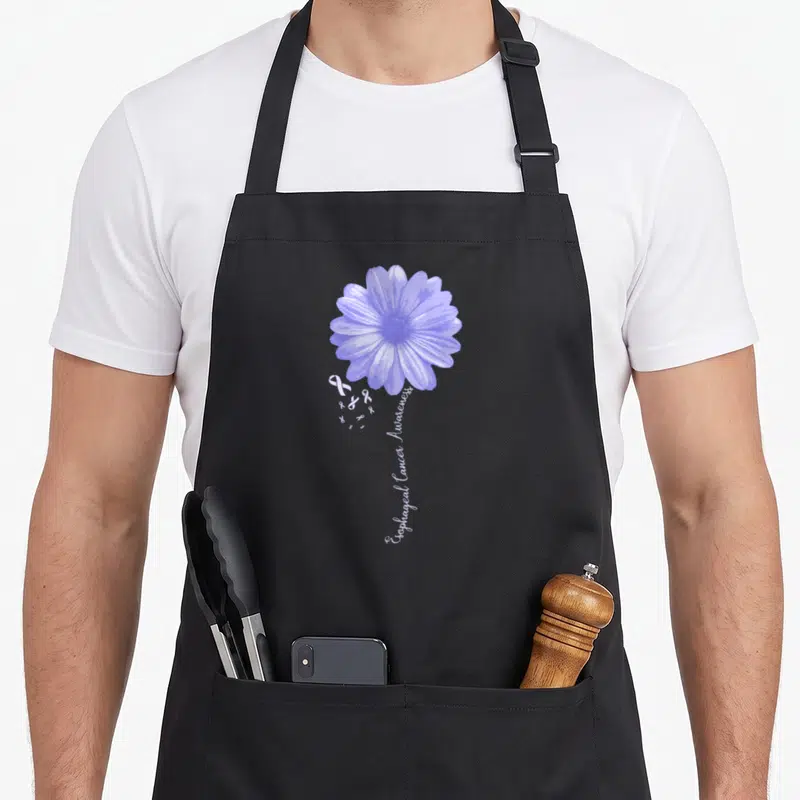 Esophageal pretty apron - Purple flower with white ribbons and vertical text reading Esophageal Cancer Awareness — shown on a black cotton canvas apron against a white background
