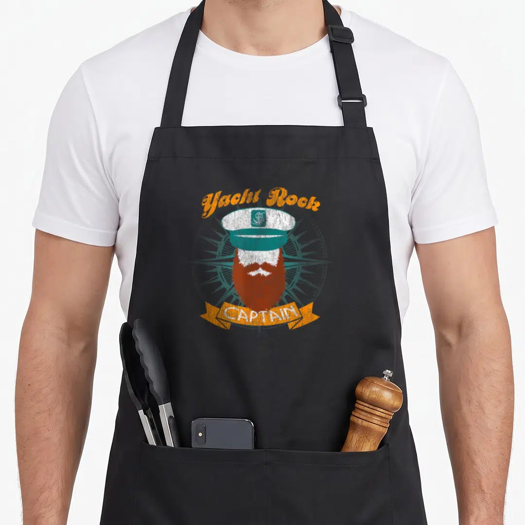 Yacht boat apron - Retro captain hat and beard with Yacht Rock arched text and CAPTAIN ribbon — shown on a black cotton canvas apron against a white background
