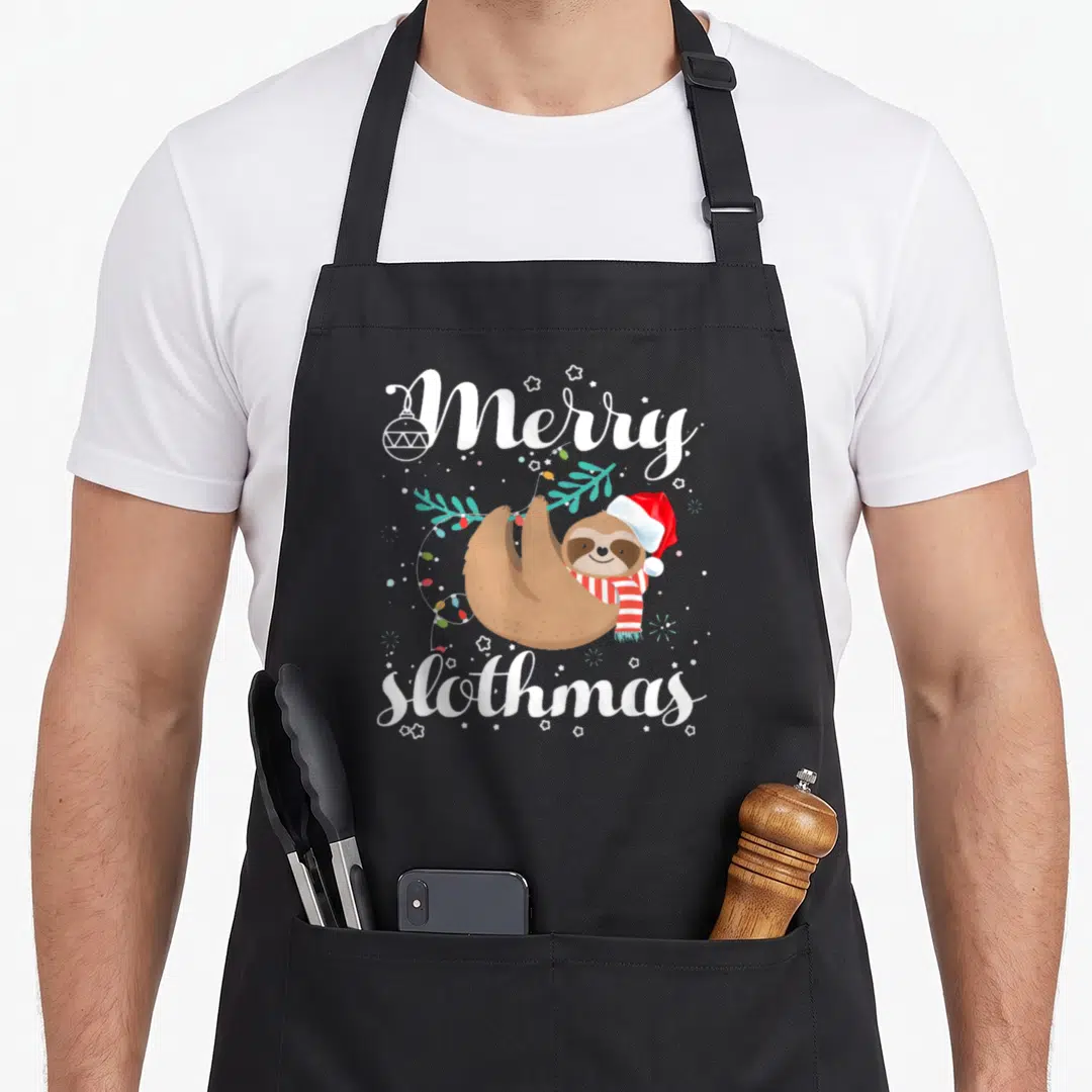 Slothmas merry christmas apron - Cartoon brown sloth in red hat and scarf with Merry slothmas text and holiday lights — shown on a black cotton canvas apron against a white background