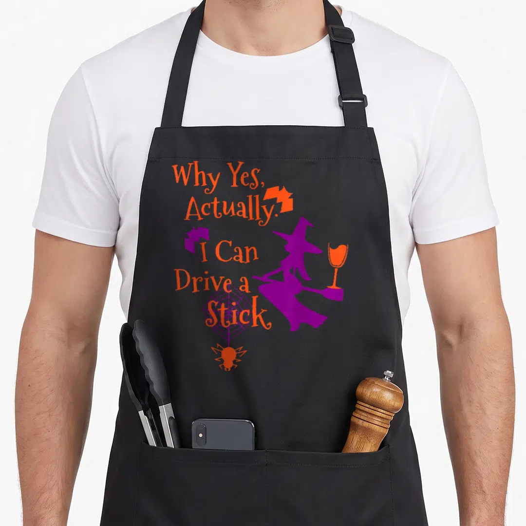 Drive halloween witch apron - Purple witch silhouette with orange text and spider web graphic — shown on a black cotton canvas apron against a white background