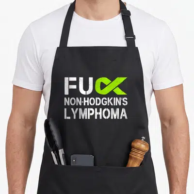 Lime ribbon apron - Distressed white text FUC Non-Hodgkin's Lymphoma with lime green awareness ribbon — shown on a black cotton canvas apron against a white background