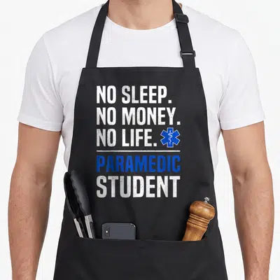 Sleep money apron - NO SLEEP NO MONEY NO LIFE PARAMEDIC STUDENT text with blue Star of Life symbol — shown on a black cotton canvas apron against a white background