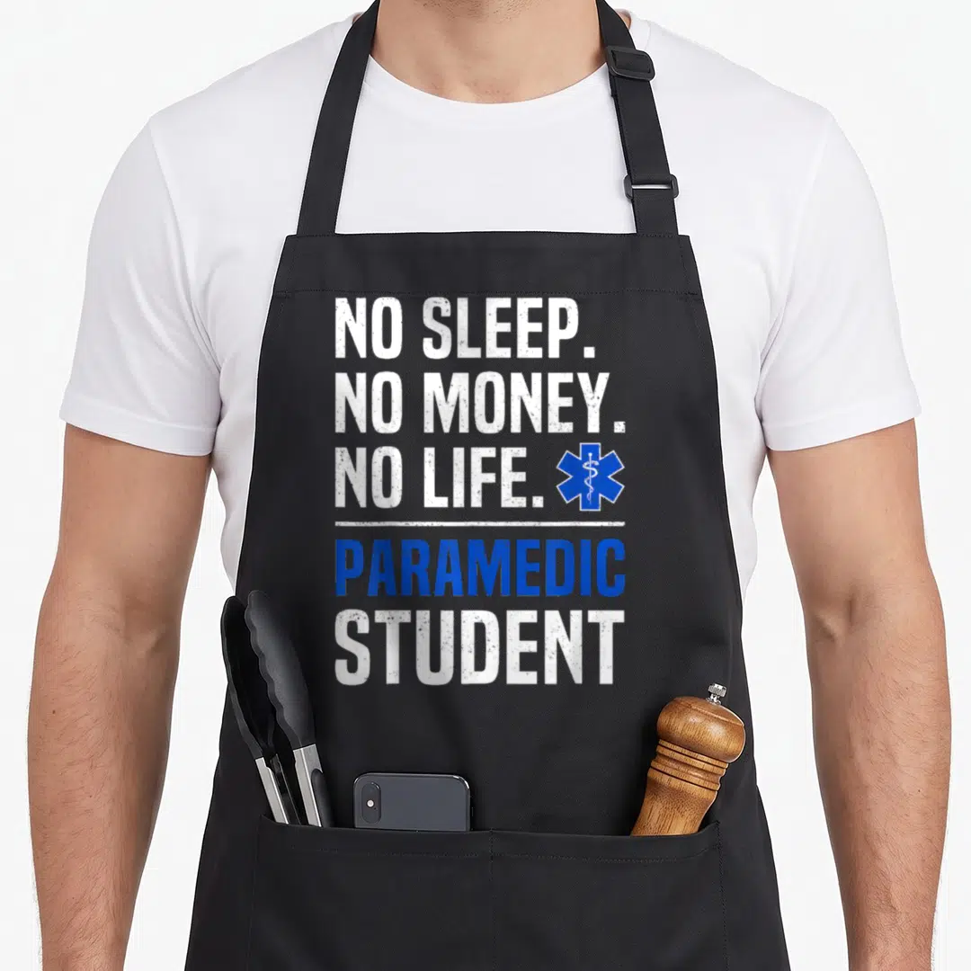 Sleep money apron - NO SLEEP NO MONEY NO LIFE PARAMEDIC STUDENT text with blue Star of Life symbol — shown on a black cotton canvas apron against a white background