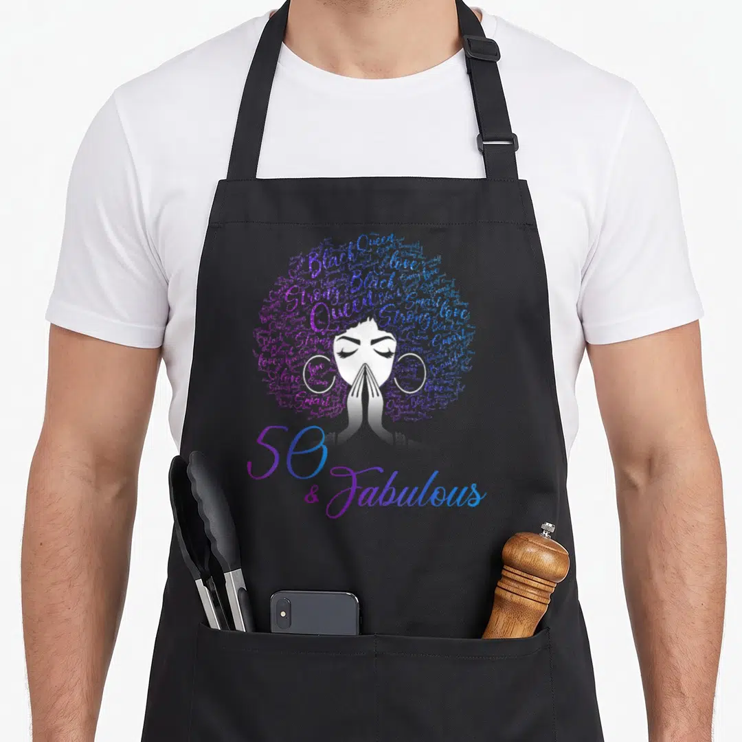 Fabulous hair apron - White woman silhouette with word-art afro and 50 & Fabulous gradient text — shown on a black cotton canvas apron against a white background