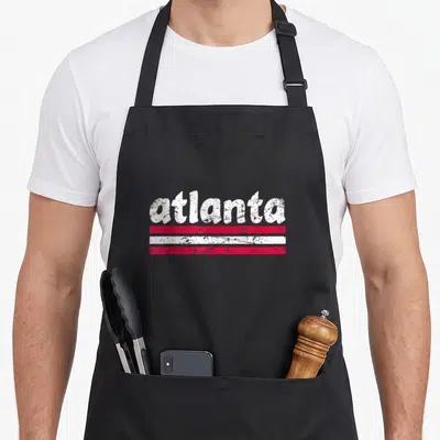 Georgia stripe apron - Distressed white atlanta text above three red white and red horizontal stripes — shown on a black cotton canvas apron against a white background