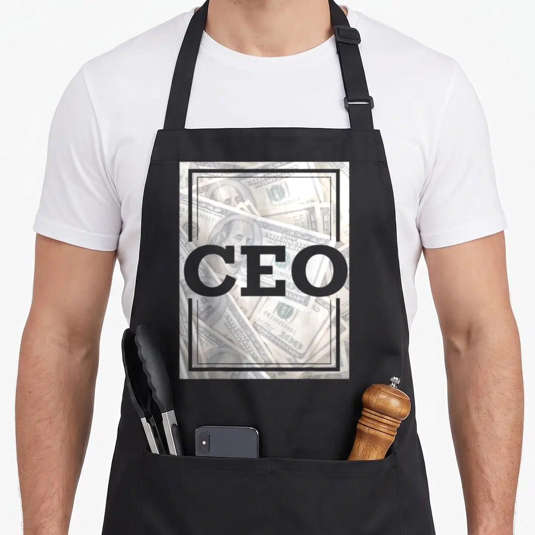 Game urban apron - Grey CEO text over scattered one hundred dollar bill photos in a rectangular frame — shown on a black cotton canvas apron against a white background