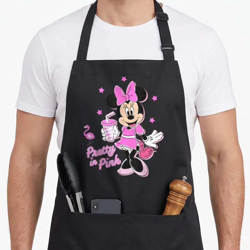 Funny pretty apron - Minnie Mouse holding cup with flamingos and Pretty in Punk text — shown on a black cotton canvas apron against a white background