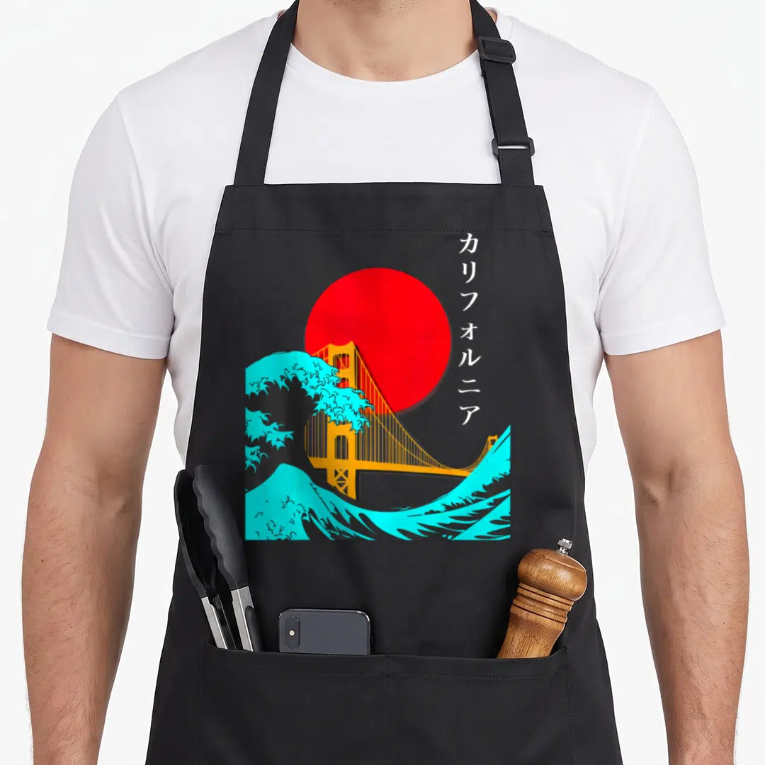 Bay japan apron - Red sun, orange bridge, cyan wave, vertical Katakana text California — shown on a black cotton canvas apron against a white background