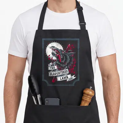Slaughtered beer apron - Stacked banner text reading THE SLAUGHTERED LAMB over a howling wolf head and knife — shown on a black cotton canvas apron against a white background