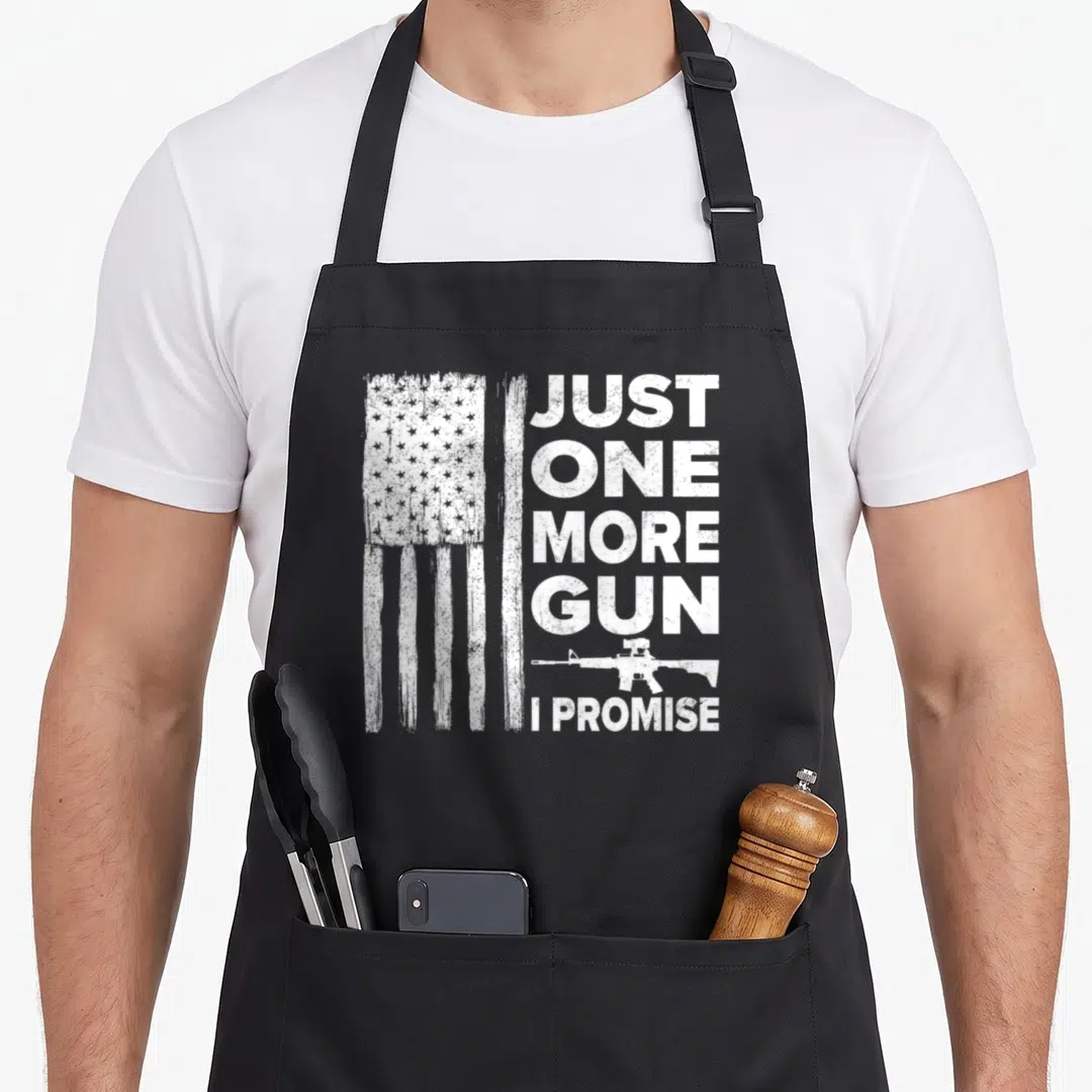 Gun patriotic apron - Distressed white flag and Just One More Gun I Promise text with rifle silhouette — shown on a black cotton canvas apron against a white background