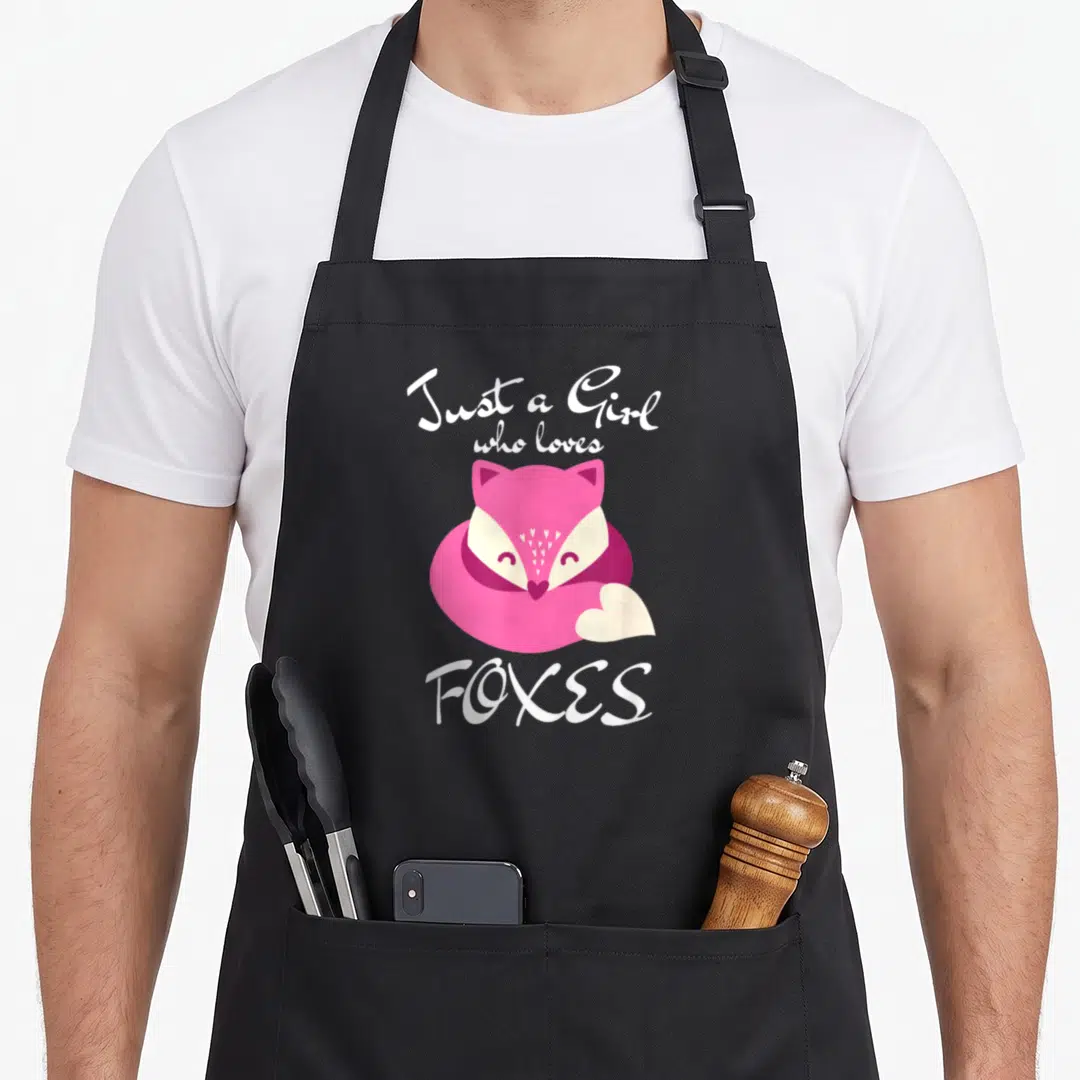 Vintage animal fox print apron - Pink cartoon fox with white hearts and text Just a Girl who loves FOXES — shown on a black cotton canvas apron against a white background