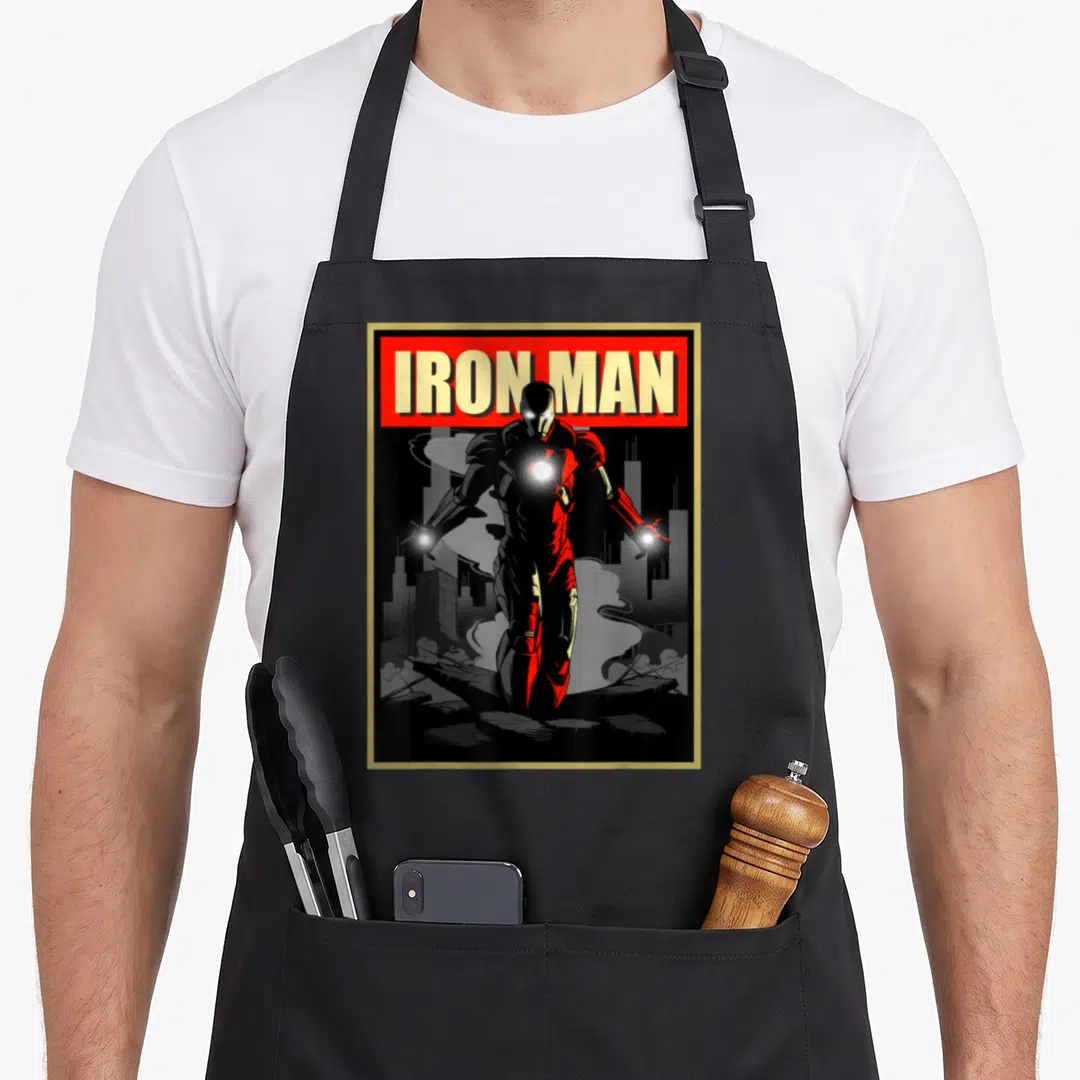 Rise ironman apron - Iron Man figure in red and black armor standing before a dark city skyline inside a gold border — shown on a black cotton canvas apron against a white background