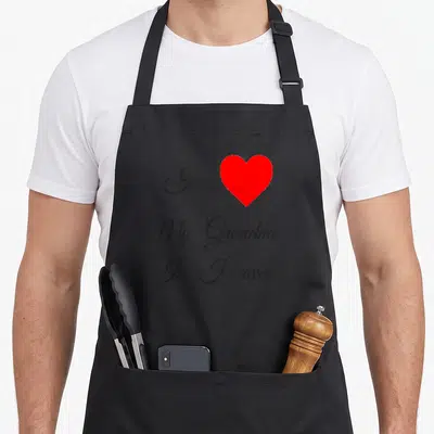 Heaven mother's day aprons - Script text I My Grandma In Heaven next to a solid red heart on grey — shown on a black cotton canvas apron against a white background