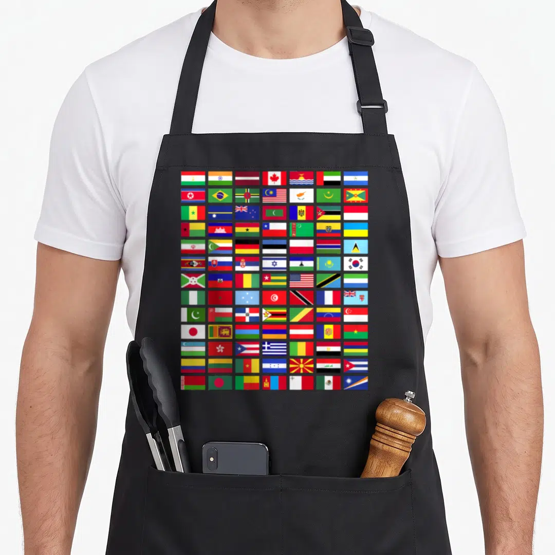 International country apron - Grid of 72 colorful national flags in red blue yellow green and white — shown on a black cotton canvas apron against a white background