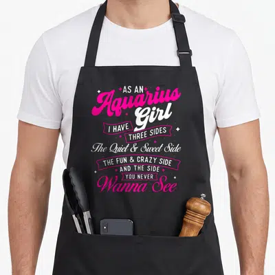 Aquarius a's aprons - Pink and white text reading As an Aquarius Girl I Have Three Sides surrounded by stars — shown on a black cotton canvas apron against a white background