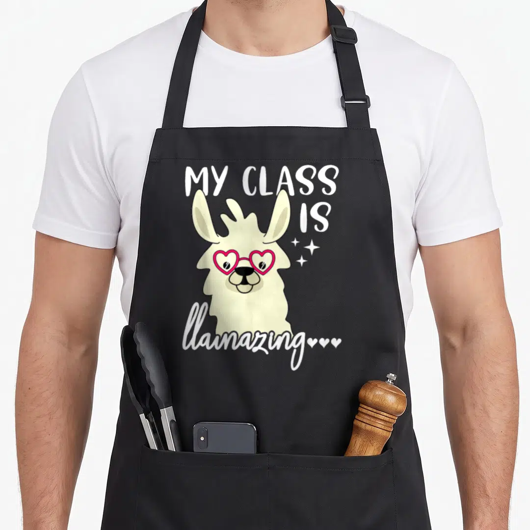 Llamazing teacher apron - Cream llama with pink heart glasses and white text reading MY CLASS IS llamazing — shown on a black cotton canvas apron against a white background