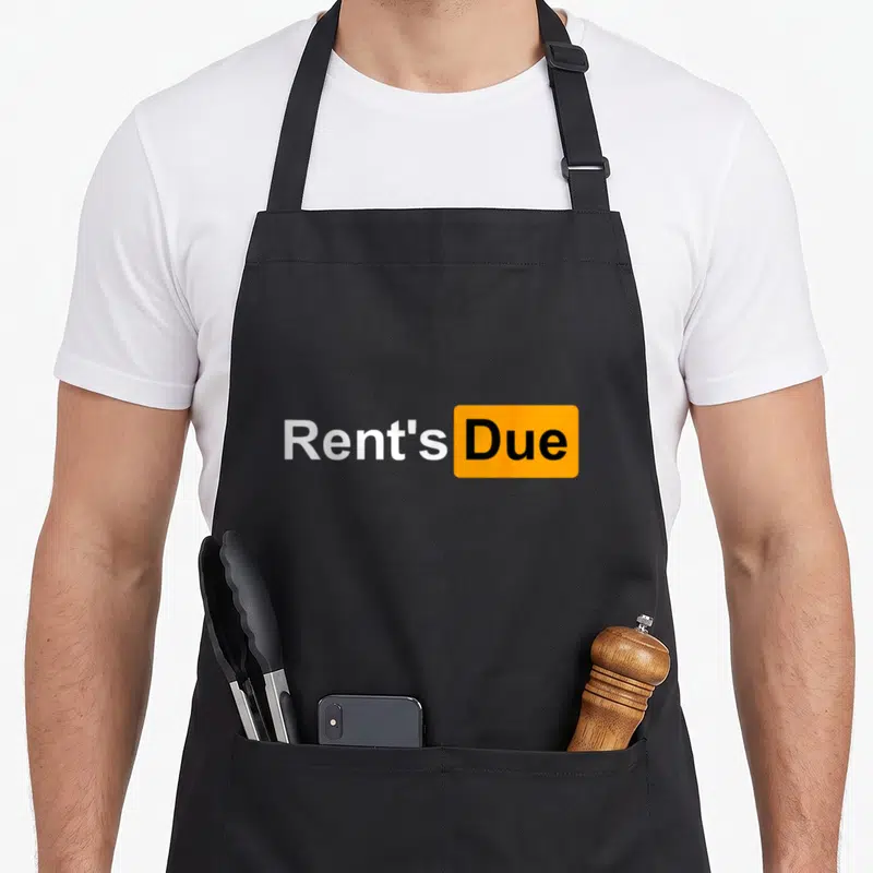 Rent roommate apron - Rent's Due text with Due inside orange rounded rectangle — shown on a black cotton canvas apron against a white background