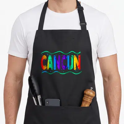 Rainbow mexico apron - CANCUN text in teal, blue, orange, purple, and green with wavy lines — shown on a black cotton canvas apron against a white background