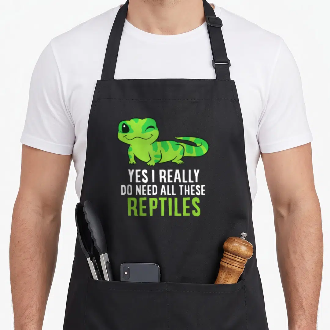 Reptile these apron - Cartoon gecko above stacked text YES I REALLY DO NEED ALL THESE REPTILES in lime and white — shown on a black cotton canvas apron against a white background